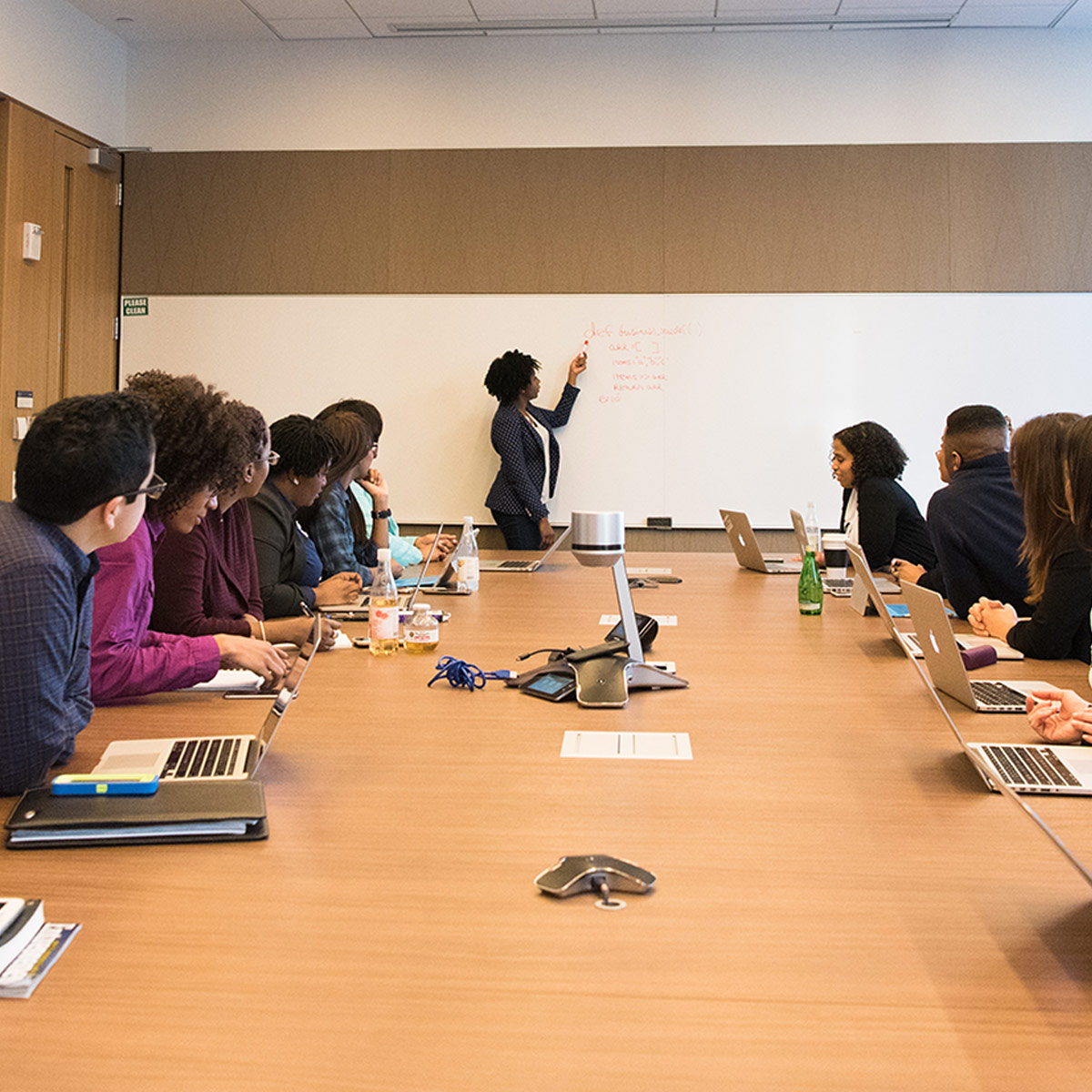 Group of people sit in a conference room and watch a presentation.