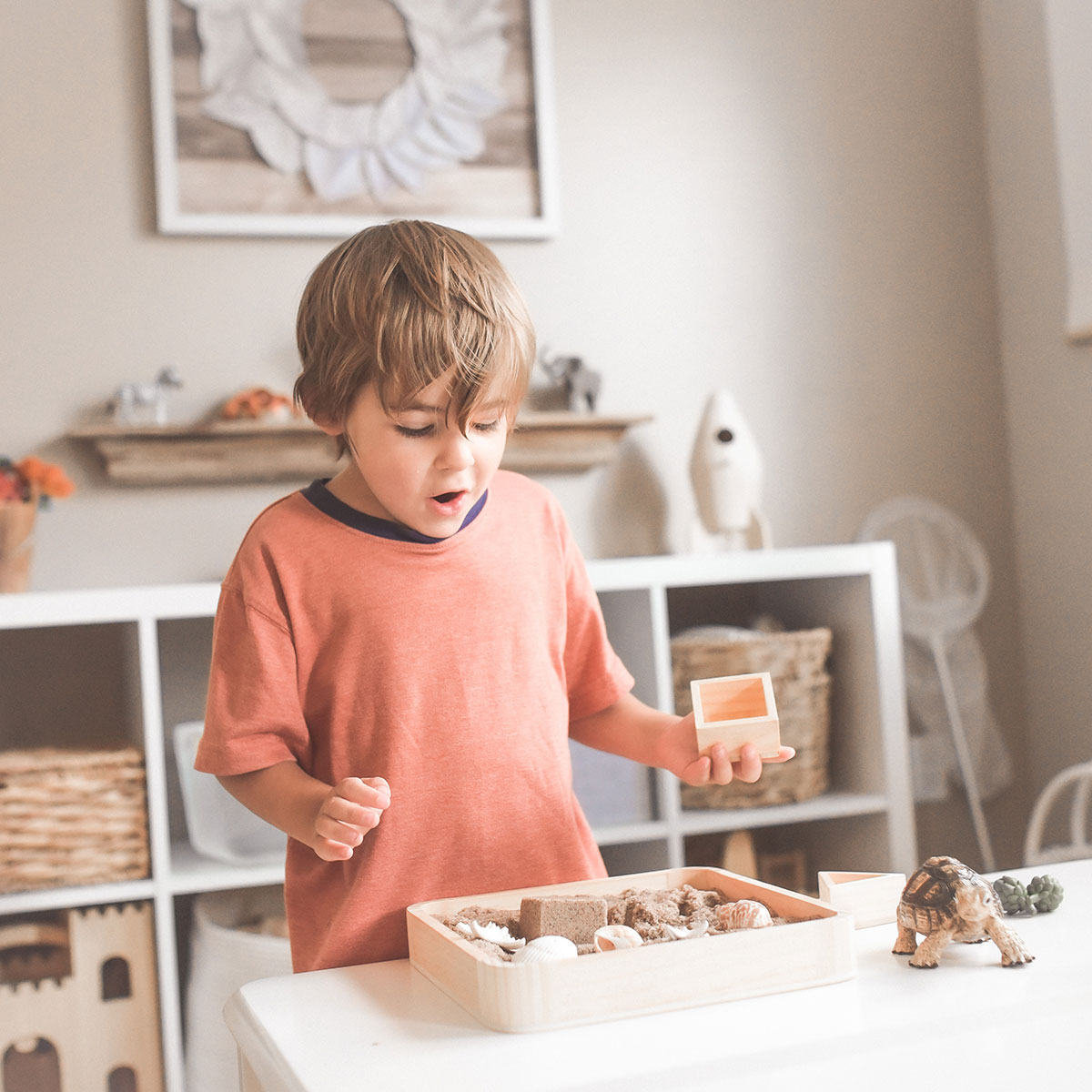 Young boy plays with sand tray table.