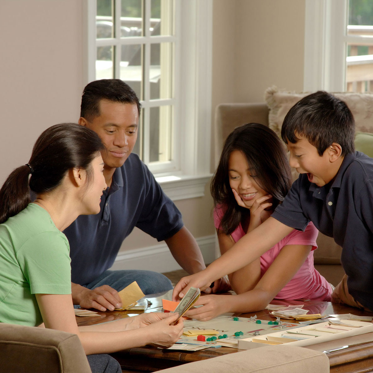 Family plays a game of Monopoly together in their home.