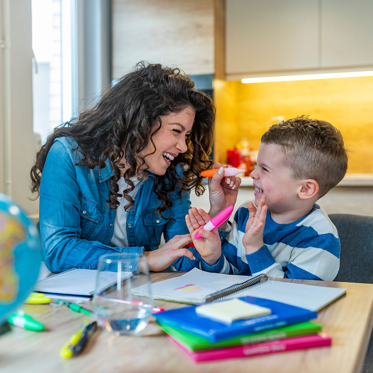 A teacher and student laugh and color together.