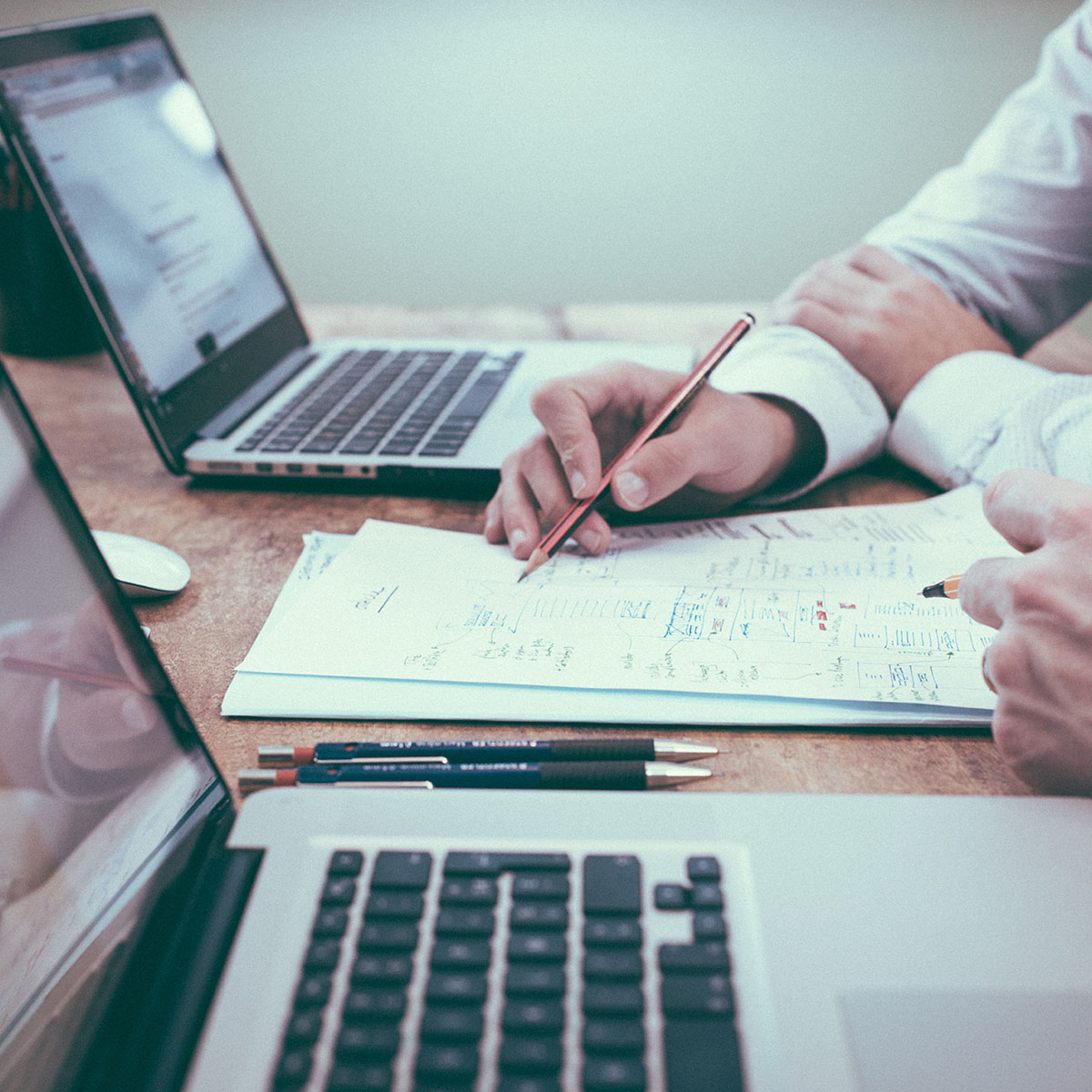 Two colleagues sit at a table reviewing documents together.