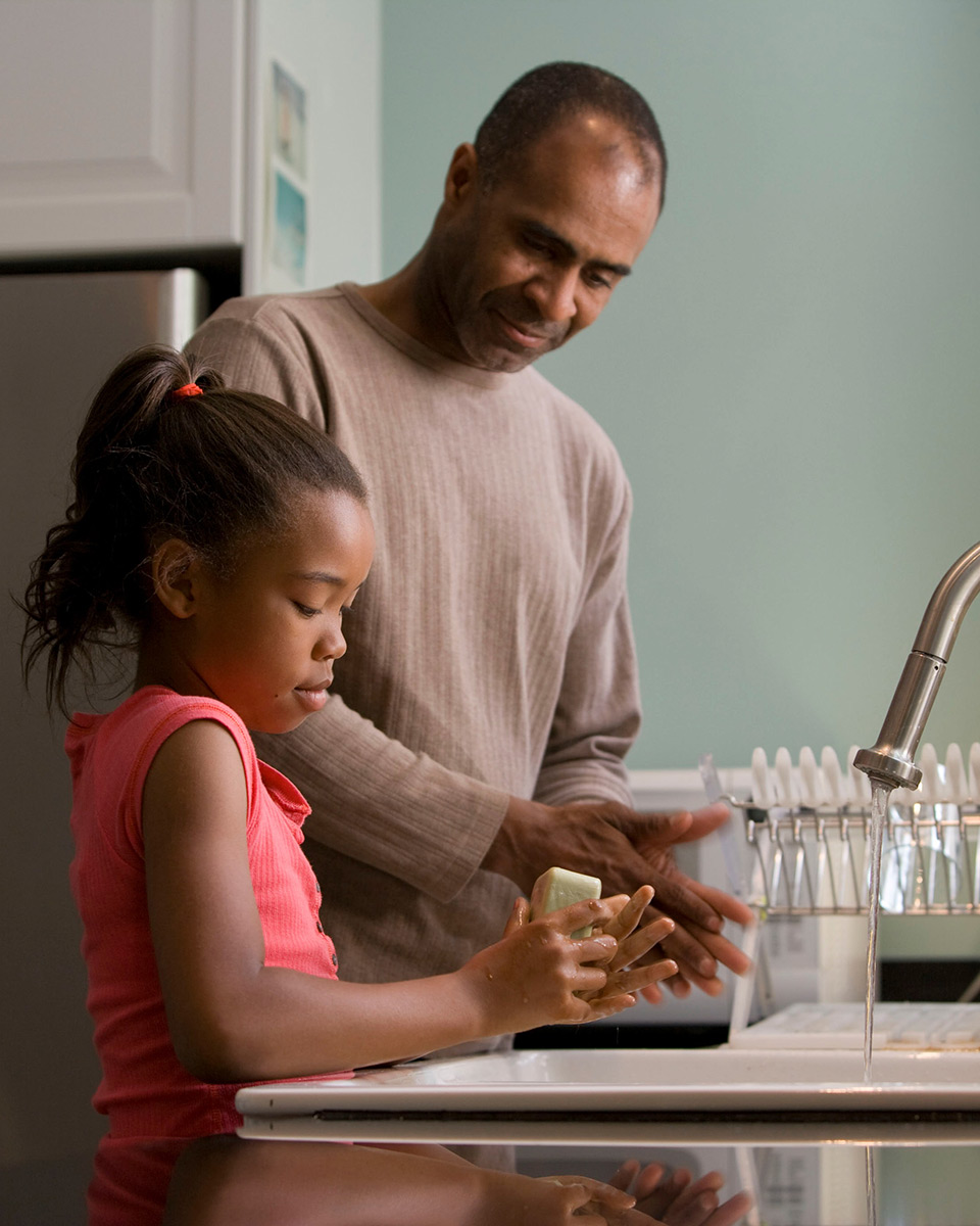 Father and daughter wash their hands together.