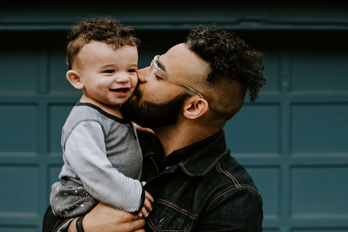 A father holds and kisses his son.