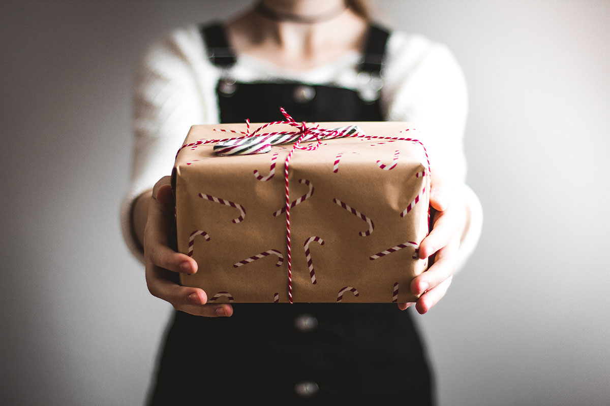 Woman holds a gift with candy cane wrapping paper