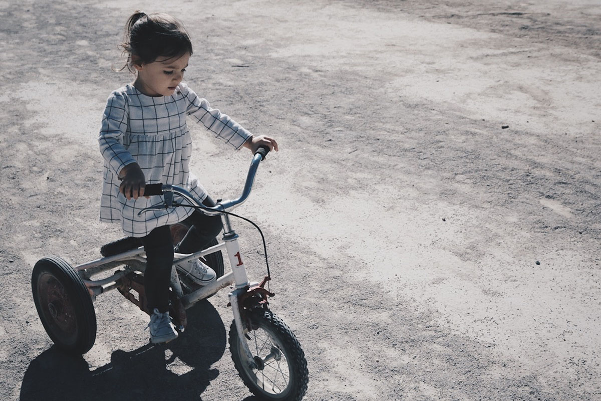 Young girl rides a tricycle outside